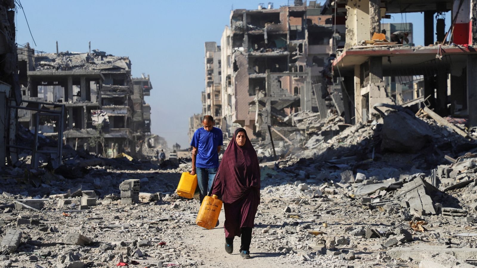 Palestinians walk past the rubble of destroyed buildings in Gaza City. Pic: Reuters